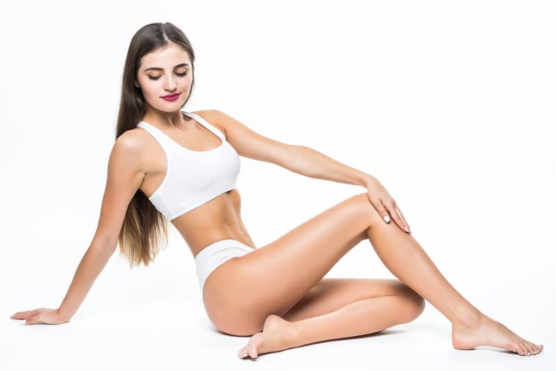 Femme assise en sous-vêtements blancs sur un fond clair, ambiance bien-être et esthétique
